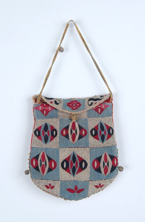 Silk tapestry pouch featuring two distinct designs. The front has a checker design with alternating light blue and silver squares containing two-pointed oval shapes that contain smaller similar shapes. With similarly designed overflap closure. The