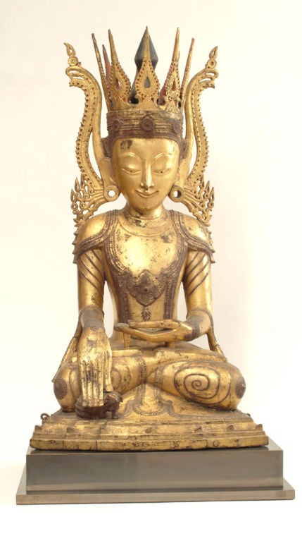 A Shaan Dynasty carved, lacquered, and gilt Buddha. Clad in a robe and wearing an elaborate crown, this buddha is seated in meditation. His right hand is in a protective position sheltering a baby elephant.