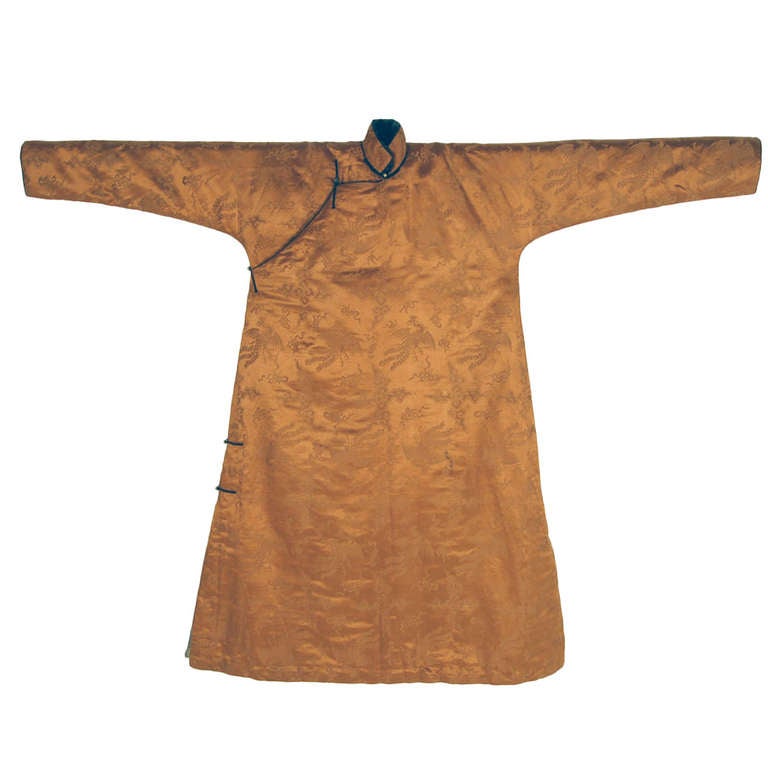 Robe made of patterned monochrome silk with phoenixes in flight against skies with cloud bands and scattered auspicious symbols. Full length garment with front overflap closing to the right, fastened with five loop and gilt metal ball toggle buttons