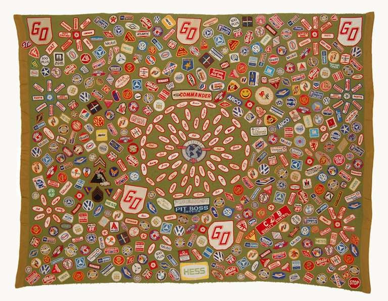 Coverlet made of commercial olive green polyester and appliqued with garage mechanics' name tags and logos of auto makers, tire manufacturers and oil companies. The corporate names suggest a mid 20th century vintage. A true folk art gem with vivid