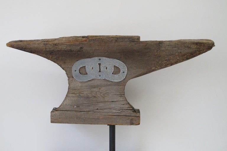 This wood anvil weathervane was mounted on top of an Odd Fellows Fraternal Lodge in Lowell, Maine from 1872. There are 3 linked rings made from zinc applied to one side. This was a lodge symbol.The well worn wooden weathervane has a metal pipe
