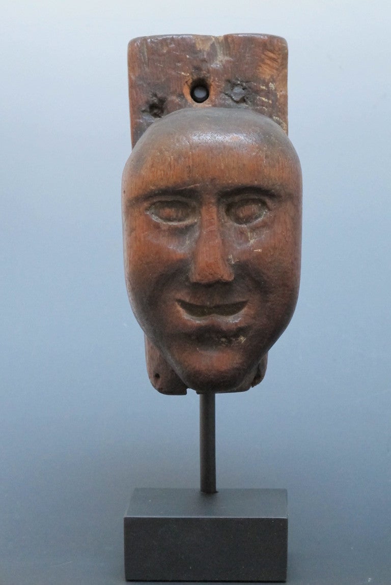Unusual wood head possibly from an early European box.  The stark face is connected to a piece of wood extending upward behind the head. Wonderful patina to the wood.  Floating over black base.