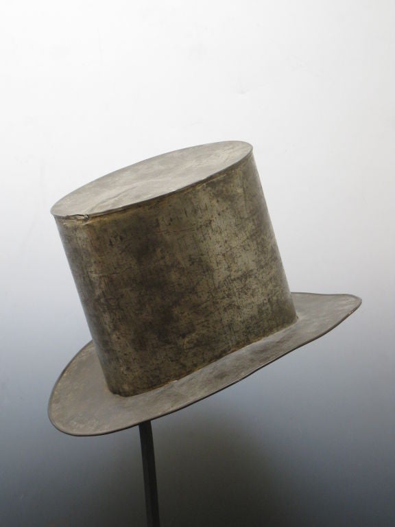 Tin smiths used to make distinctive tin gifts for 10th anniversaries in the past. This formal tin top hat was probably a treasured anniversary gift in the 19th century now mounted on a black metal stand.  A related example is on view at the American