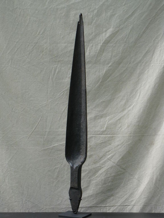 Forged iron tool for making the holes in the center of wagon wheels with hooked end to hang a weight. Minimal sculptural form now  mounted on a metal base.