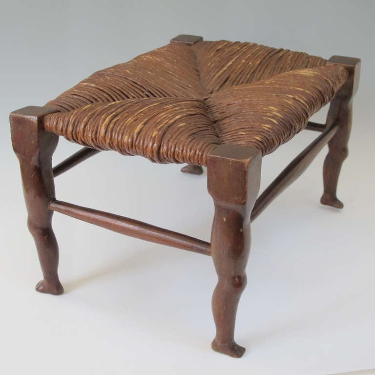 Finely carved stool with 4 shapely human legs  and original rush top.  The small stool is carved and mortised of mahogany with stained nut brown finish. The figural legs are robustly carved. Being a leg man this folk piece was irresistible.