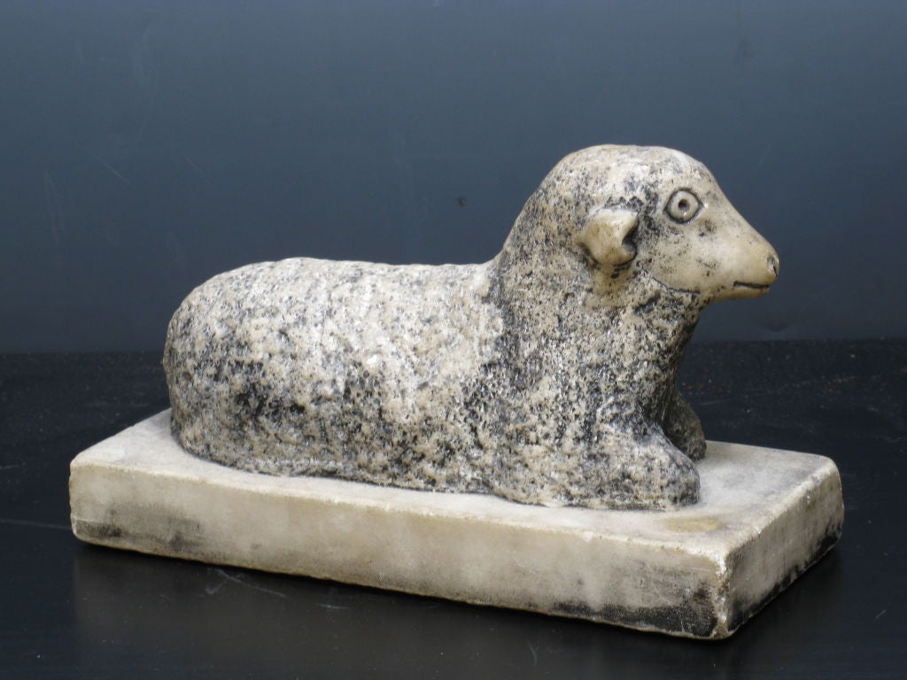 Early marble carving of a lamb on a platform.