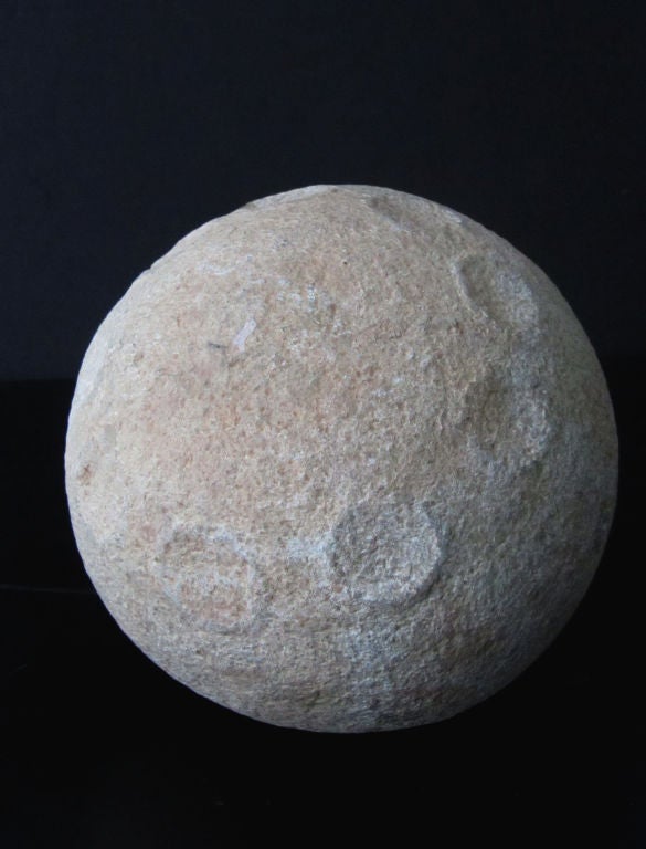 A remarkable stone sphere with 2 rings of 9 round indentations circling the top and bottom hemispheres. Not only are the circular markings perfectly carved into the stone, but they have a raised edge from the surface of the ball as you get when a