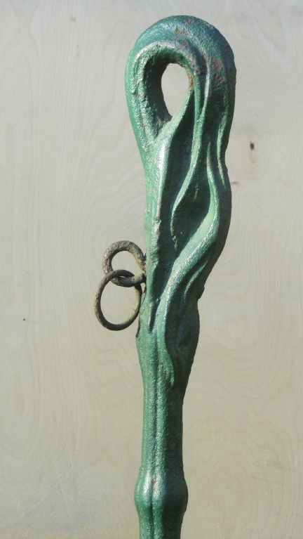 Cast iron hitching post for tying down the horse in earlier days. Striated stepped form with graceful top in old green paint with iron rings. Mounted on metal base.