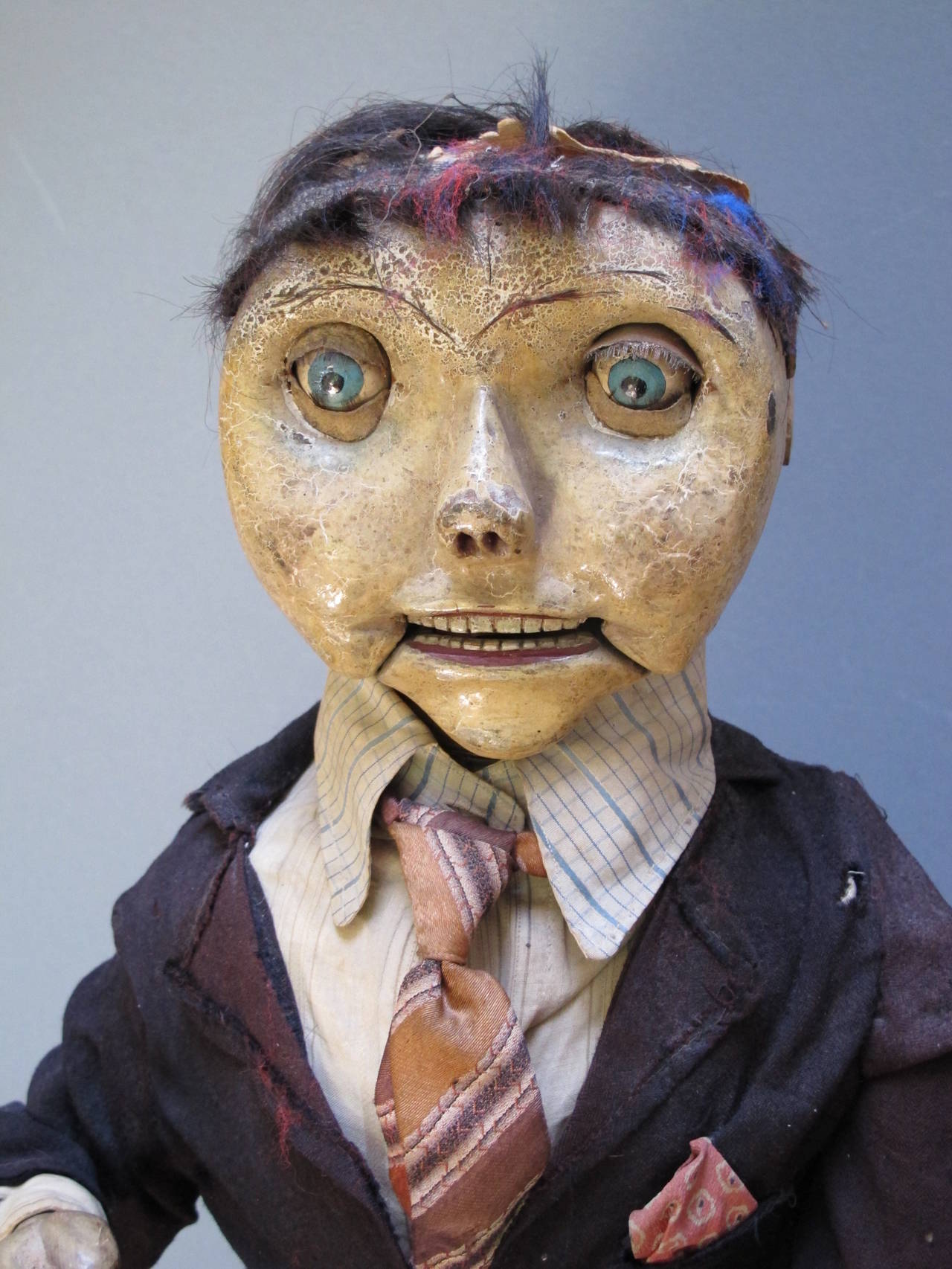 The early ventriloquist figure has a carved wood head with articulated mouth and great painted surface. The moveable arm has well carved hands in different positions. He is well dressed in suit and tie and has small leather shoes on.
The figure has