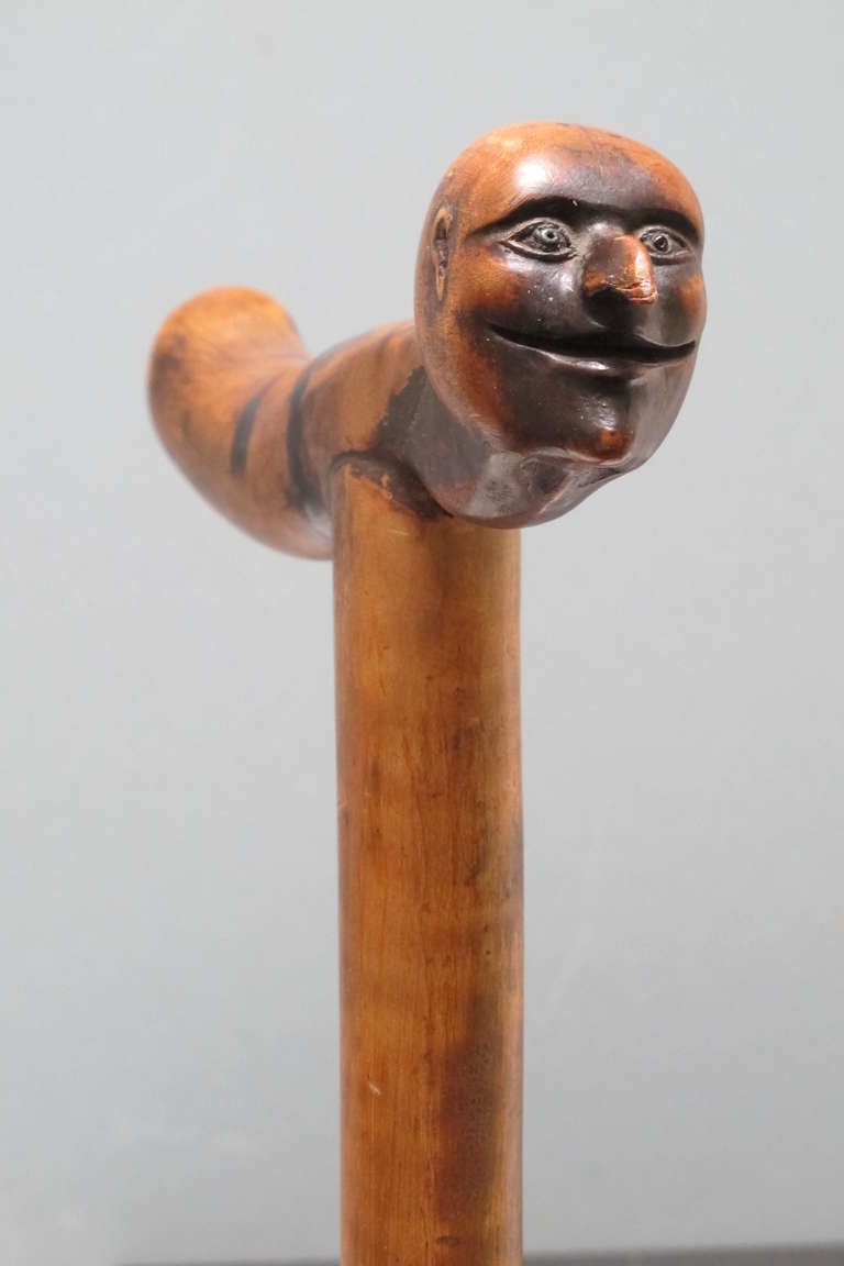 Well used walking stick with handle terminated in the head of a grinning man with beaked nose. The shaft appears to be tiger maple with the top joined and carved separately. The cane has a nice well used patina. I sold this cane some 25 years ago