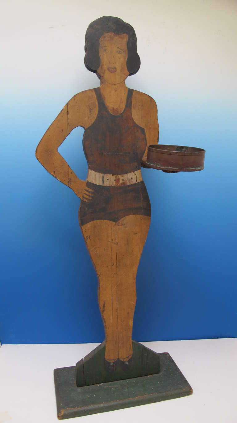 Painted cutout of a lady in a bathing suit holding a copper cup. I'm not sure if she was a smoking stand or serving/holding something. My choice would be peanuts.
The paint is well preserved with minor wear.