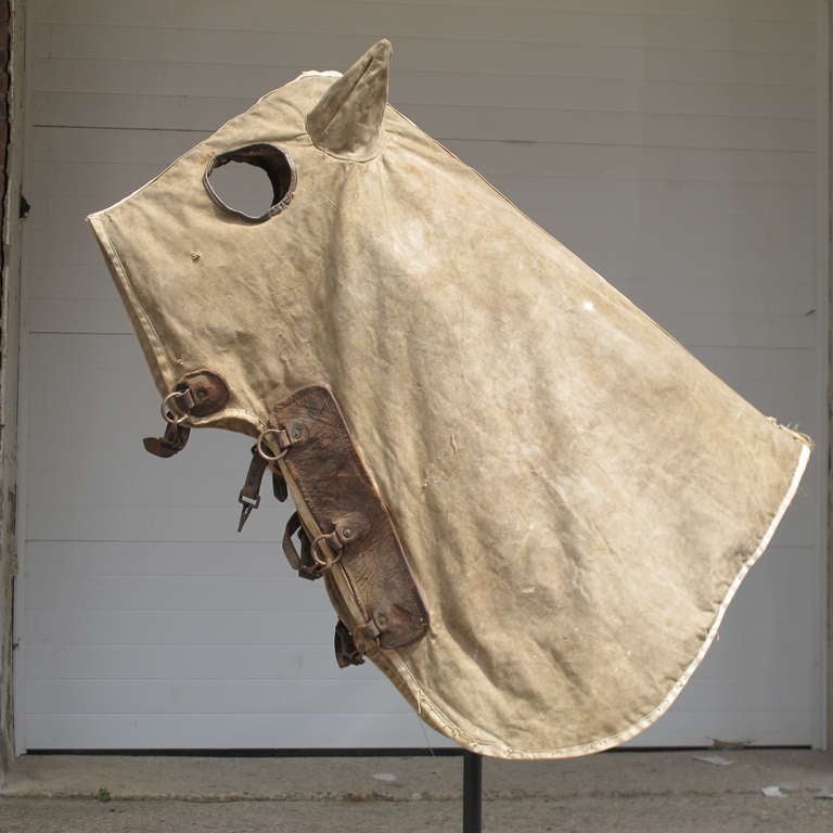 Horse cloaks were used for warmth and to protect the horse from vicious biting horse flies. The ears were especially sensitive. Used primarily for thoroughbred horses. This cover is canvas with leather around the eyes and at the front clasps area.