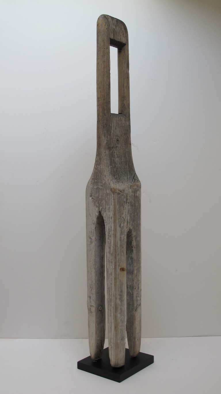 Before washing machines were invented laundry would be stirred by hand using wooden paddles, sticks, and agitators.
This for pronged wash stirrer was an unusual form with a rectangular hole in the flattened top. It has a bleached wood surface where