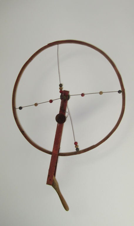 A graphic early American bent wood hoop toy with handle and movable wood beads on wire spokes with clacker bell.  Wall bracket mount allows it to float in space.