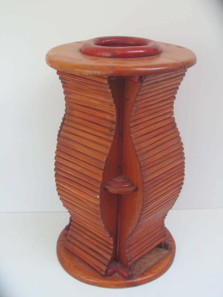 Unusual pieced wood umbrella and cane stand of undulating form. The wave shaped sides are made up of horizontal rounded strips of wood that extend from the round disc top and bottom. The opening of the stand is at the top with a red dyed circular