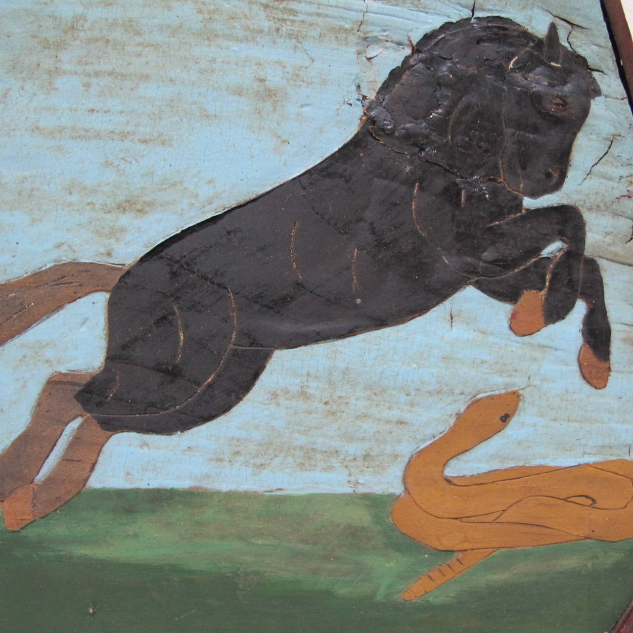 Unusual Folk Art painting on faceted wood panel of a black horse leaping over a rising rattlesnake. The eight sides piece of wood has subtle carving to the horse that enhances the painting. There is wood edging framing the piece. From a Ct private