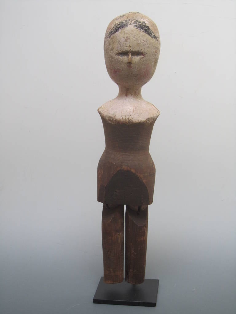 A wooden doll survivor from the 18th century. The turned body and head have the classic form of of the Queen Anne period. This abstracted figure retains some of its paint on the head and shoulders with the face having minimal features.The legs have