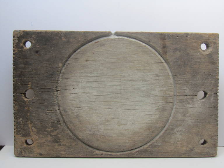 In early cheese making part of the process was pressing the cheese to extract the watery part. The board has a carved circular groove which channels the water to a notch for draining. On either side are a series of holes for posts that connect to