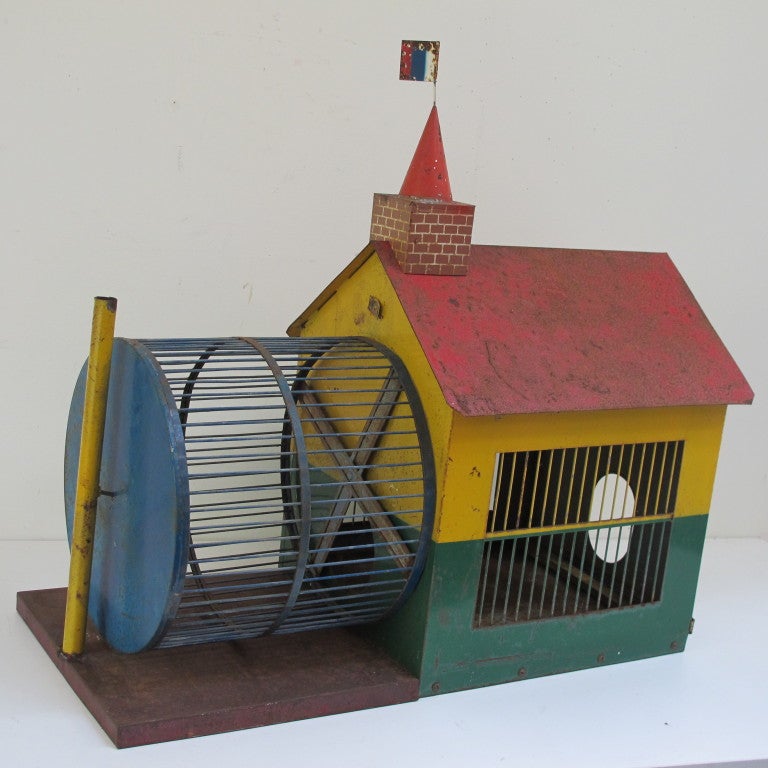 Graphic tin house with attached wire running wheel.  It could have housed hampsters or other critters. Well designed with hatch door on end and clean out tray topped with a tin flag.