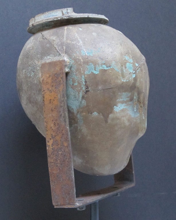 Copper head mold with iron bracket that came from a doll factory.  The life size head is of abstracted form with an old oxidized patina along with brown/gold paint.  It has a  hollow for neck attachment below and an opening at the top with lid. in. 