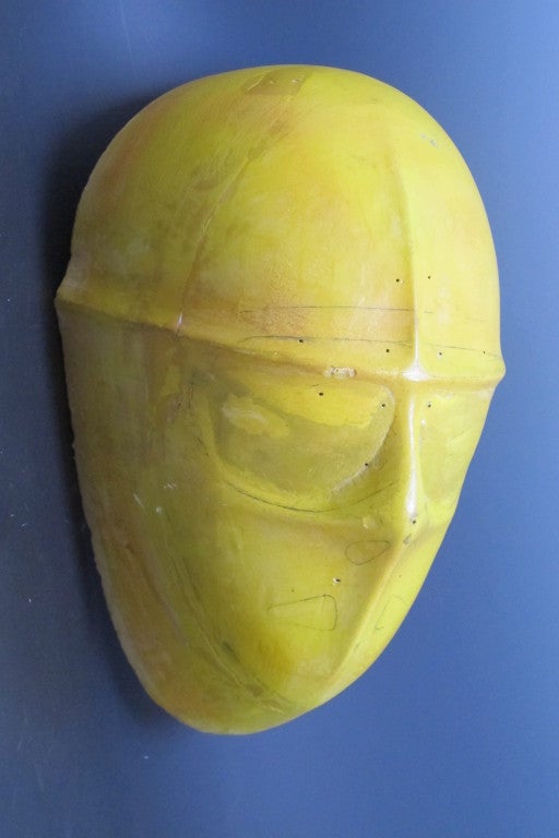 Sculptural hockey mask mold pencil markings and drilled marker holes. Yellow tinted plaster with a hard surface coating. There is a hardware hanger loop on the hack for wall mounting.