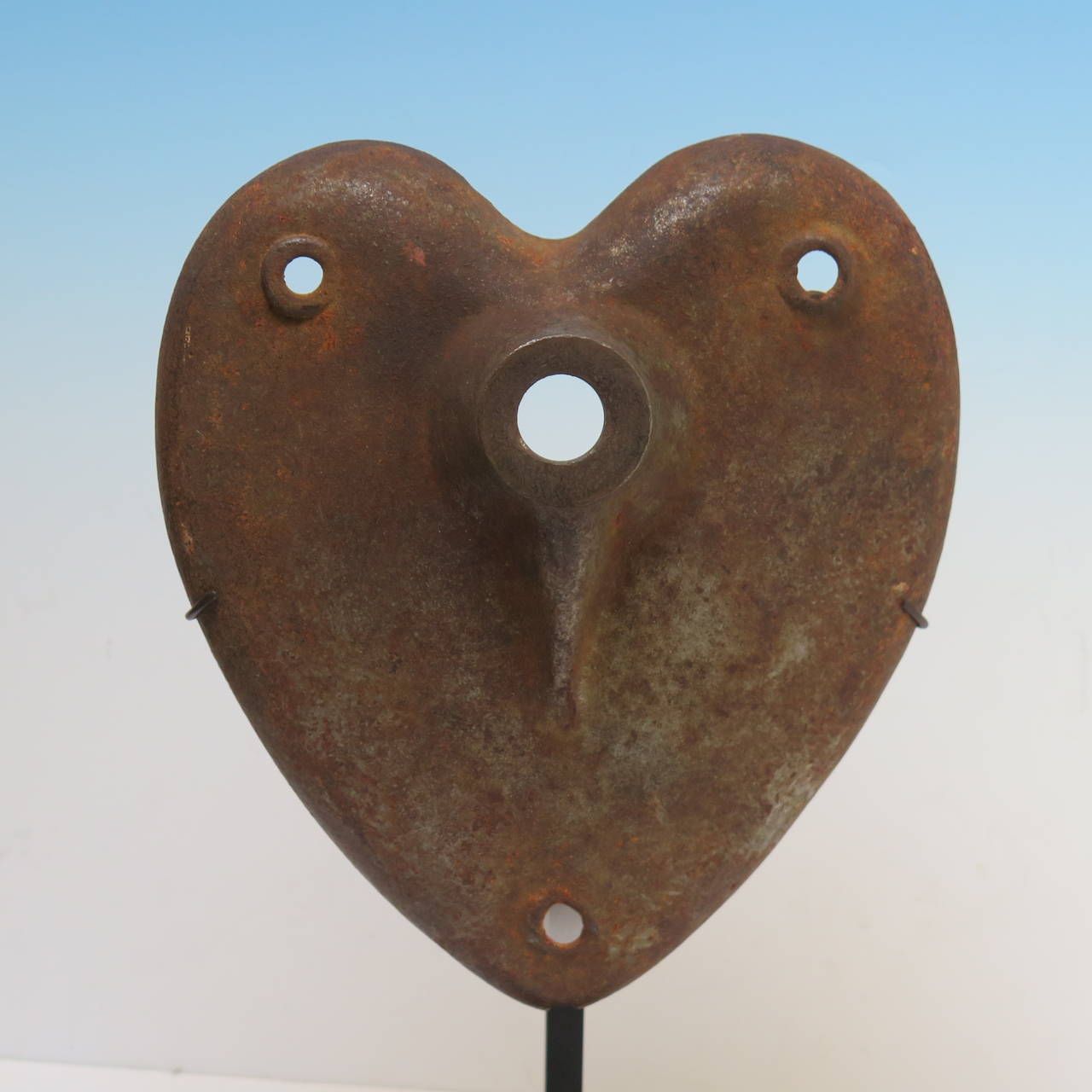 A large iron Industrial heart form with three holes for attachment and a larger raised central hole possibly for a rod or shaft. This piece came to me from Iowa which might suggest it came off of some farm machinery. The rounded shape is beautifully