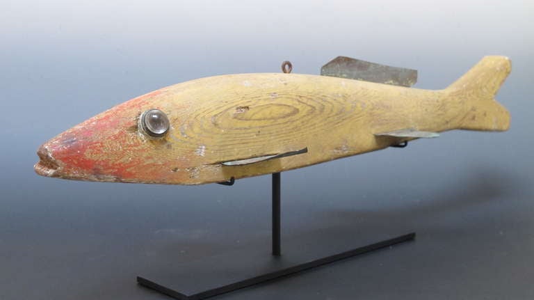 This is an unusually large fish decoy of carved and painted wood
with copper fins and reflective glass eyes. Fish decoys like this would have been lowered into the water through a hole in the ice on a frozen lake in Michigan. The well used decoy