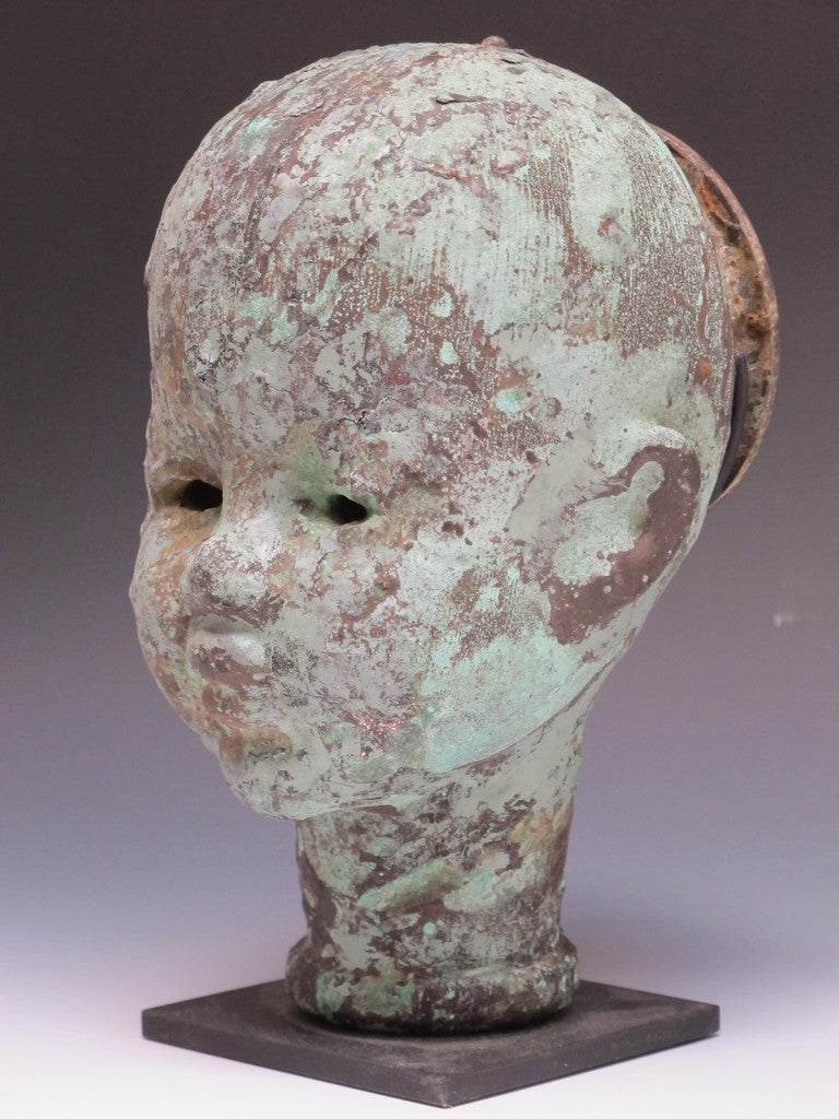 This is one of the largest molds for making doll heads I have seen.
The elegant form of the serene head is enhanced by the long neck.
Made of copper with variegated patina and mounted on a black metal base.The back of the head is open to insert