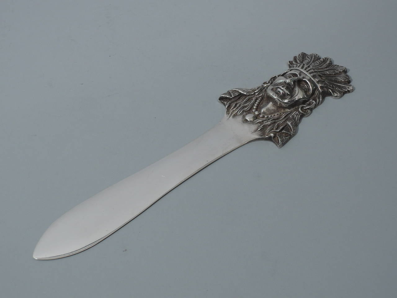 Sterling silver letter opener with Native American motif. Made by Black, Starr & Frost in New York, ca. 1900. Handle is bust of Indian chief with feathered headdress. Fine cast with clear details and good patina. Hallmarked. 

Length: 10 ½ in.