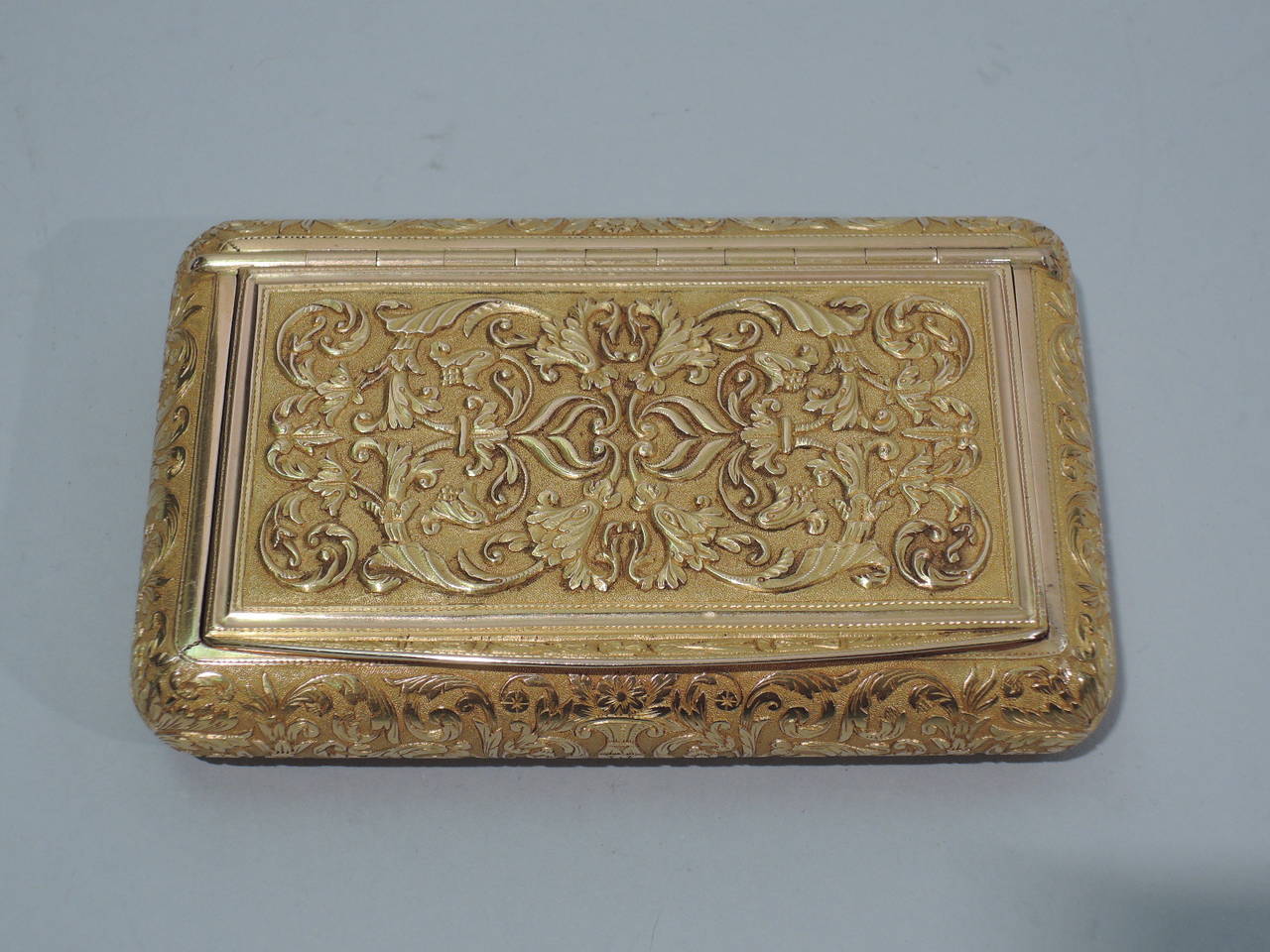 European 18k gold snuff box, ca. 1900. Rectangular with round corners. Cover is hinged with flared tab. Tooled scrolls, foliage, and flowers. On bottom is engine-turned wave ornament. Hallmarked 750 (that is, 18k gold).

Dimensions: H ¾ x W 3 ½ x