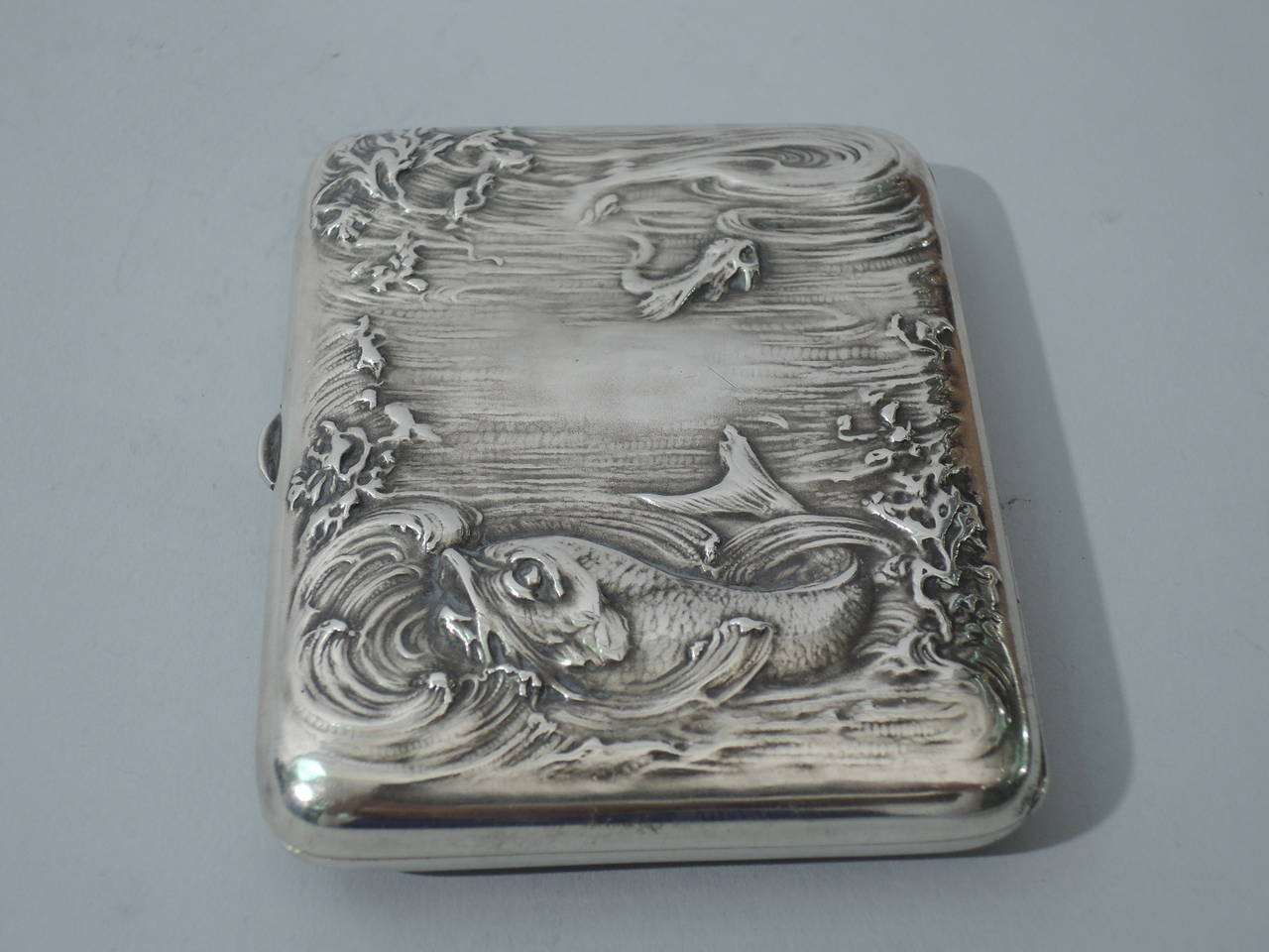 Sterling silver cigarette case with marine motif. Made by R. Blackinton in North Attleboro, Mass., ca. 1900. Rectangular and hinged. Chased and repousse double-sided aquatic scene: water, plants, and fish. Interior gilt. Hallmark includes model no.