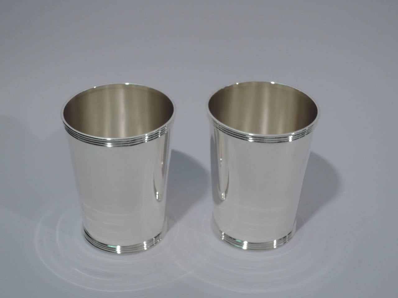 Pair of sterling silver mint julep cups. Made by Whiting in New York. Each: straight sides and reeded rim and foot. Hallmark includes no. 5 and phrase Old Kentucky Mint Julep Cup. Excellent condition. 

Dimensions: H 3 7/8 x D 3 in. Total weight: