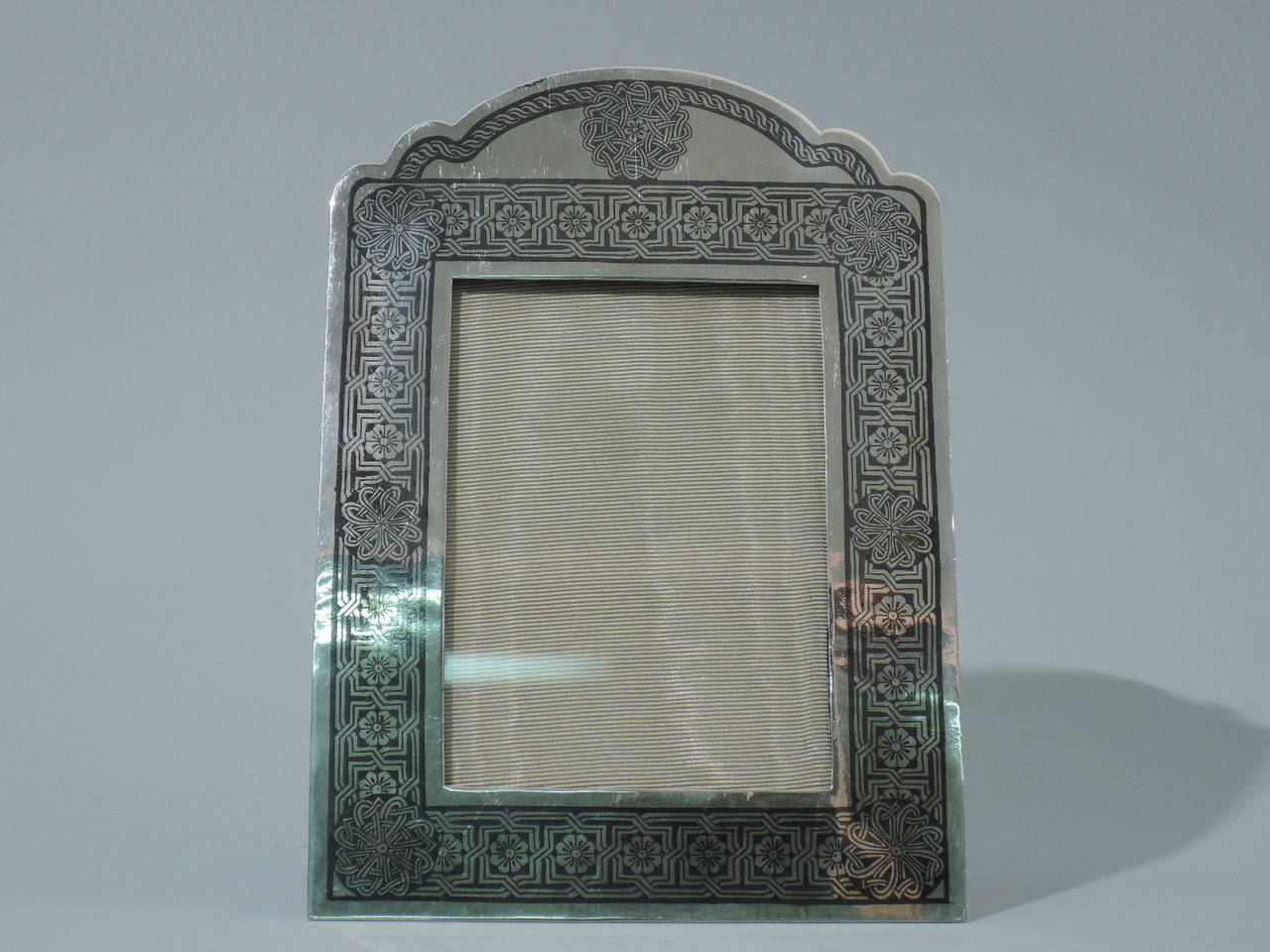 Exotic Persian silver picture frame, circa 1920. Rectangular window bordered by niello fretwork inset with flowers, and wheels with interlaced scrollwork at corners and top. Top is arched and scalloped with cable border. Perfect for a special