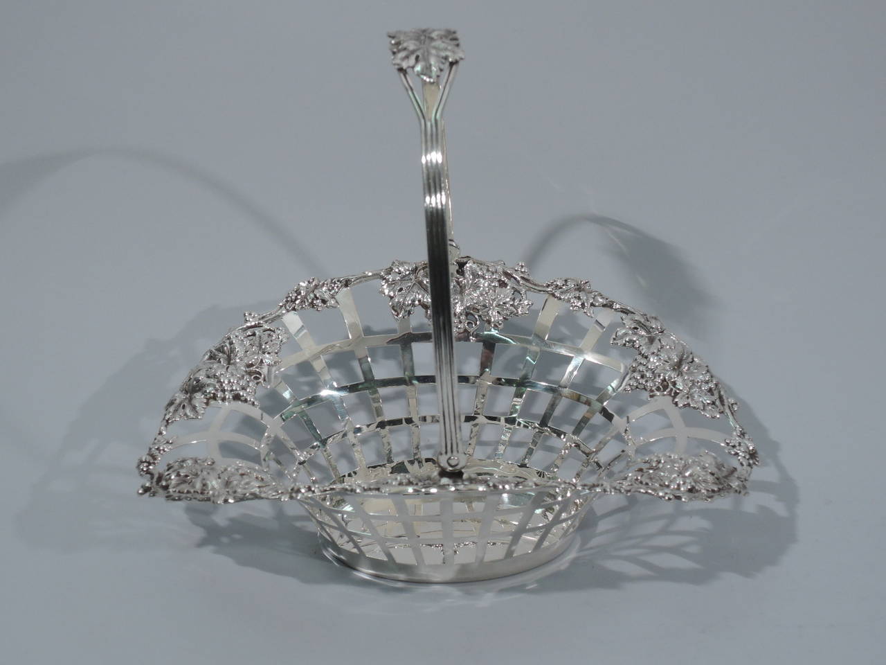 Sterling silver basket with grape bunches. Made by Lebkuecher in Newark, circa 1900. Sold and oval well. Sides are open lattice with flared mouth. Vine rim with grape bunches applied to interior. Reeded and tapering swing handle with central leaves.