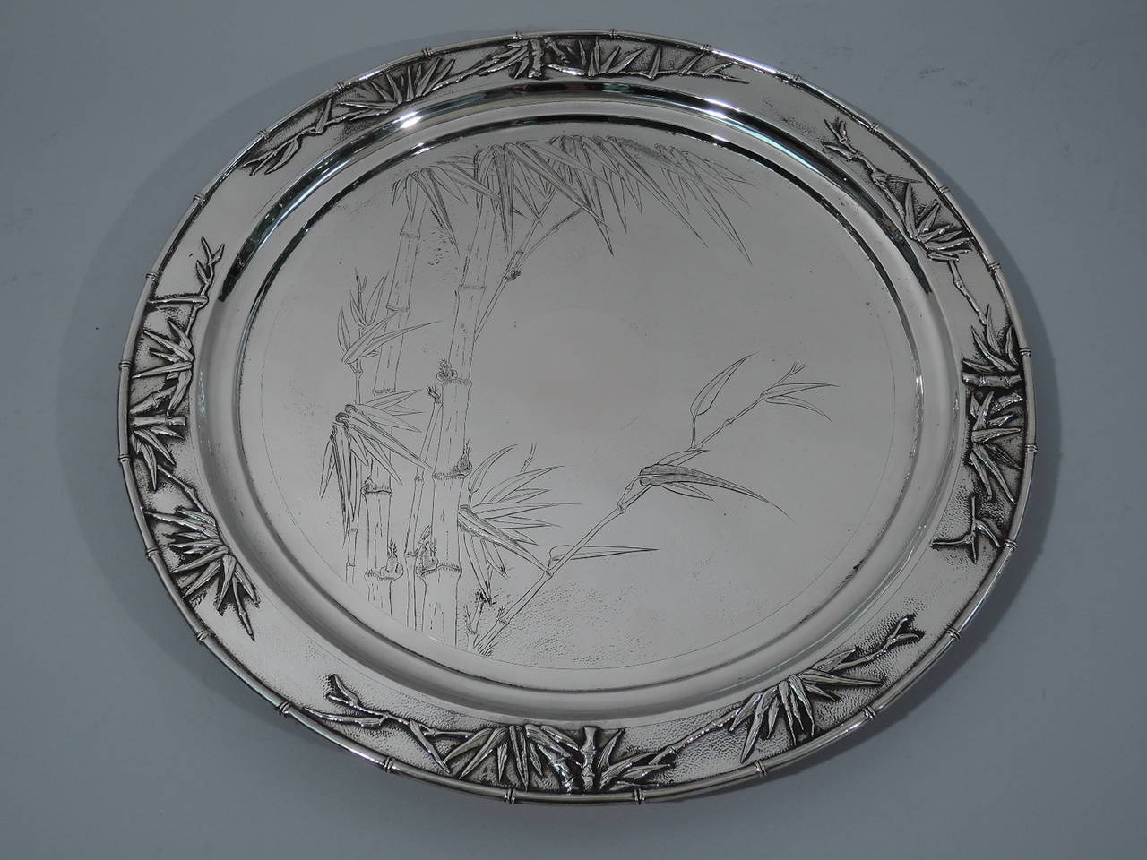 Export silver bamboo tray. Made by Zee Wo in Shanghai, circa 1900. Circular with three half sphere supports. Well has engraved bamboo and central circular cartouche. Rim is bamboo with applied leaves. All-over stippling. A beautiful piece for