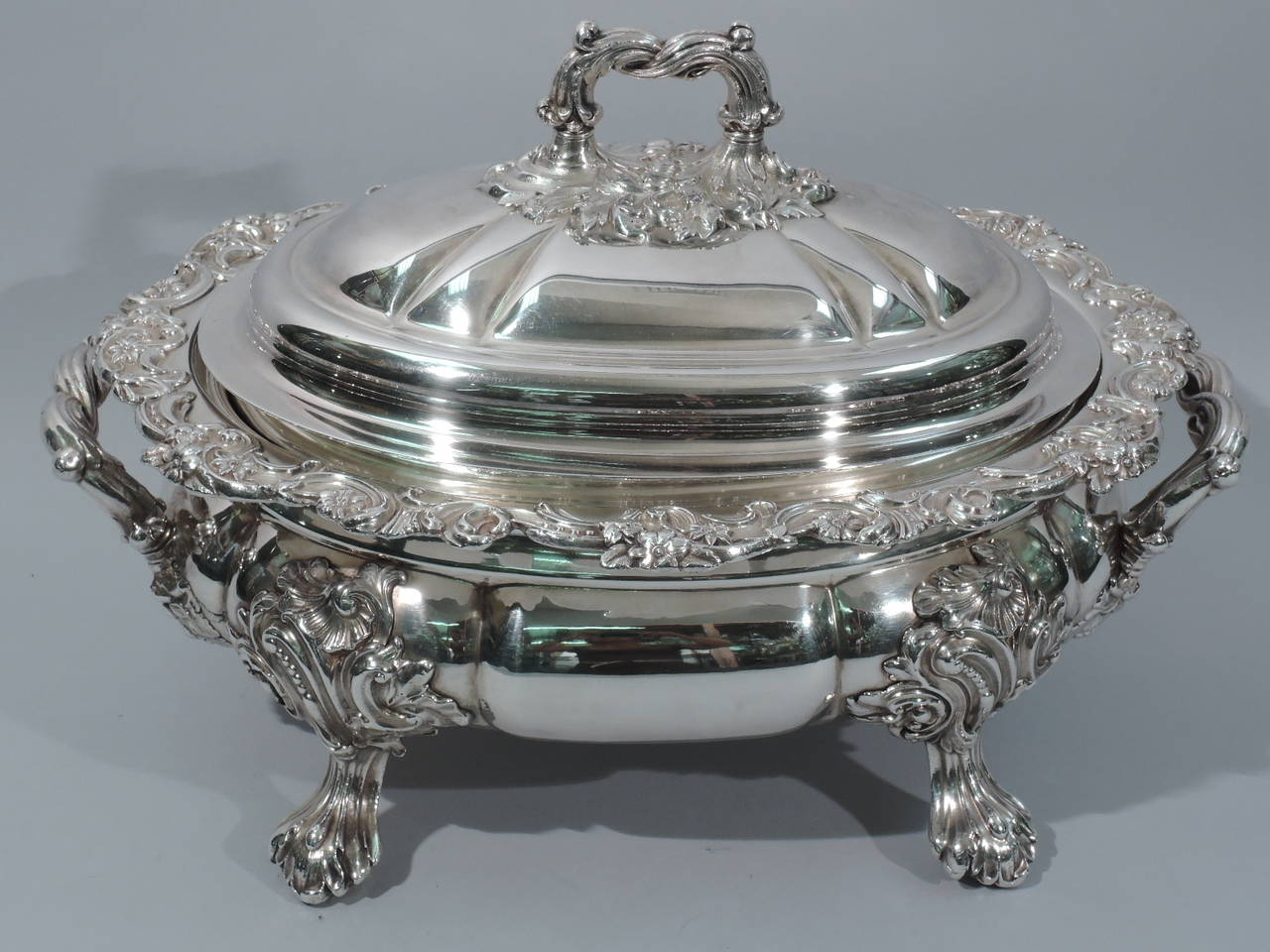 Georgian Sheffield plate soup tureen, circa 1820. Body is squat and lobed. Ornate mounts terminating in four paw supports. Scrolled bracket end handles with foliate mounts. Flat rim with applied scrolls and flowers. Cover is domed and lobed with