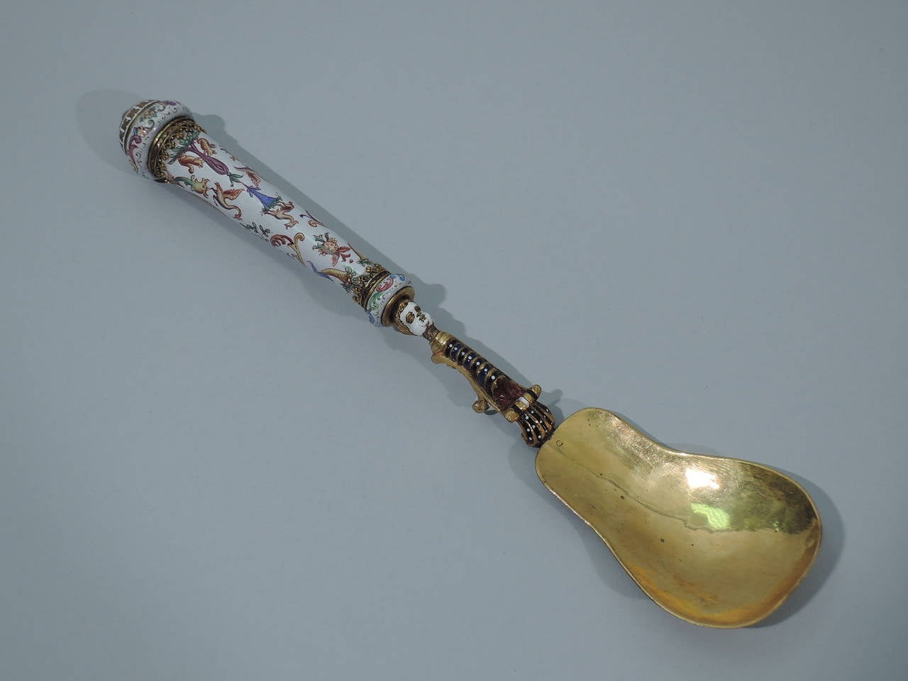 Set of 3 Italian serving pieces in gilt brass and enamel, ca. 1860. This set comprises a spoon, fork, and knife. The handles are straight and tapering with knops and enameled Grotesque ornament on white ground. The spoon has a shaped bowl. The fork