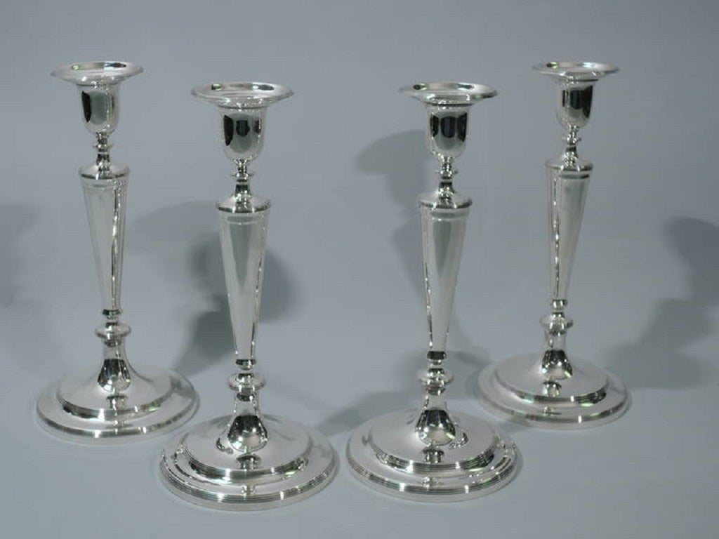 Set of four sterling silver candlesticks. Made by Tiffany & Co. in New York, circa 1908. Each: straight and tapering shaft on knop on stepped foot. Urn socket on knop with detachable bobeche. Reeding. The pattern (no. 17267B) was first produced in