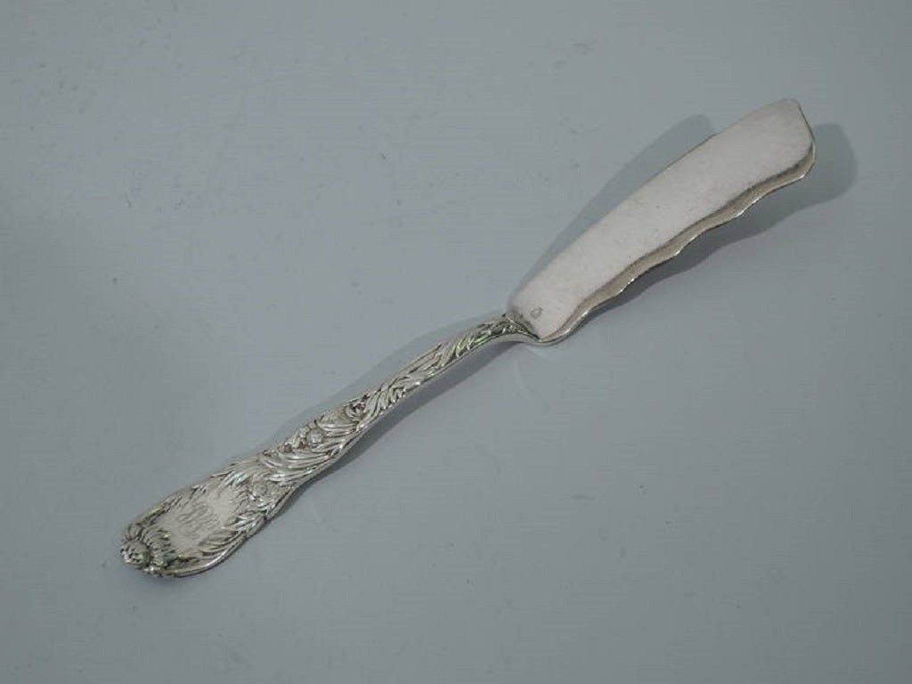 Sterling silver serving master butter in Chrysanthemum pattern. Made by Tiffany & Co. in New York, ca. 1890. Double-sided ornament. Curved blade with wavy top rim. This form also tentatively identified as a pickle knife (Tiffany Silver Flatware, p.