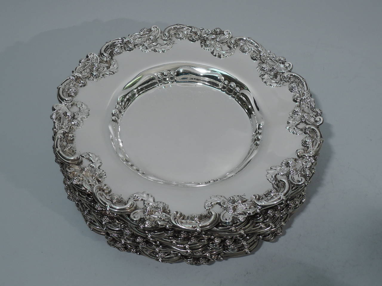 Set of ten sterling silver bread-and-butter plates. Made by Graff, Washbourne & Dunn in New York, circa 1910. Each: plate has well with chased and repoussé geometric ornament. Scrolls foliage, and flowers applied to rim. Hallmark includes model no.