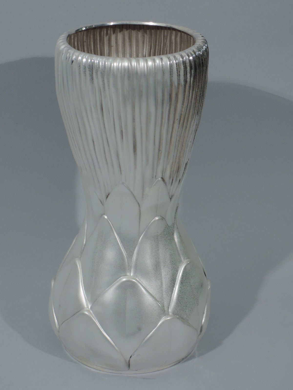 Unusual sterling silver vase. Made by Tiffany & Co. in New York, circa 1992. Round with softly chased abstract foliage and flared and reeded top. Concave middle. Hallmark includes copyright date 1992 and phrase “Tiffany Studios Collection Designed