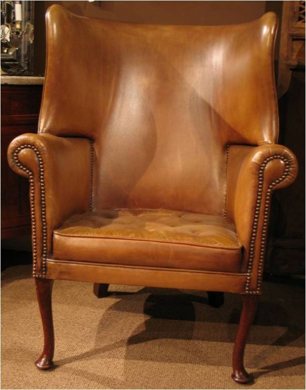 CON22477   <br />
A 19th.c. English barrel back wing form arm chair. The solid wooden frame with exposed Queen Anne inspired mahogany legs. Full hide leather, tufted seat cushion.                               44 in. H x 31 in. W x 31 in. D