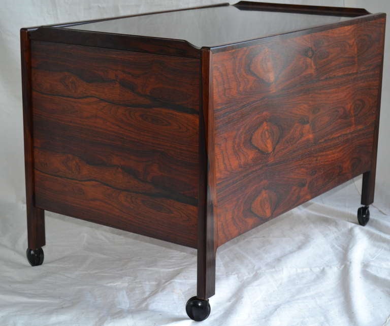 Unusual rosewood and beech bar with sliding black laminated top that hides a liquor cabinet behind three drawers. Great case piece for use as an end table and dry bar. Stamped 