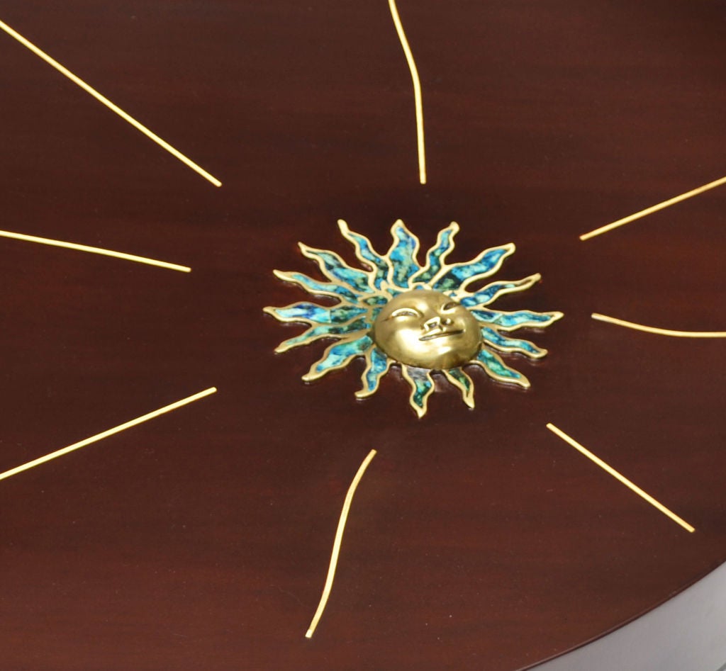 A striking mahogany cocktail table from 1958 by Pepe Mendoza. The 3- dimensional enameled brass mask of the sun surrounded by polished brass rays are inlayed as a dramatic design across the surface of this unusual coffee table

The sculptural low