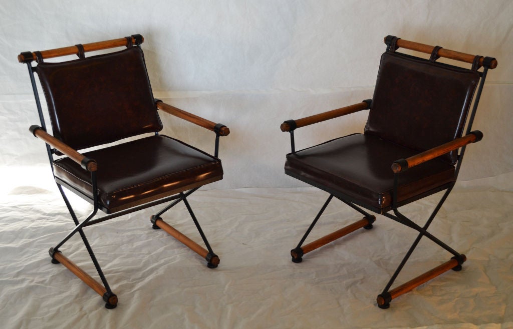 A pair of 1960's oak and iron campaign style armchairs with faux brown leather cushions in the style of Cleo Baldon. This pair of vintage chairs is in excellent vintage condition and is viewable at our Laguna Beach location please contact 
Located