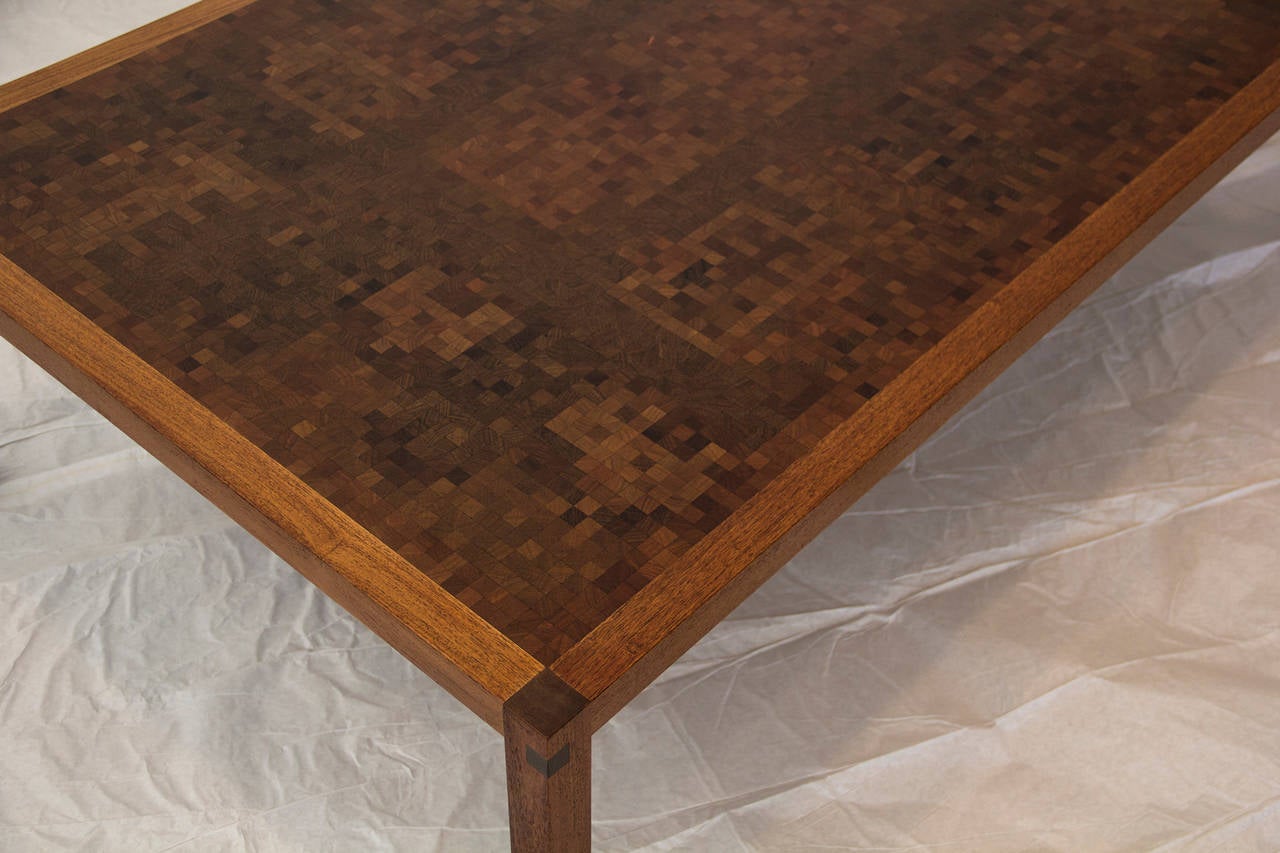 Table basse danoise fabriquée à la main par le Studio Tranekaer, encadrée en teck, datant des années 1970.  
Le plateau est une grille composée de 1800 blocs de plus d'un pouce de carrés de teck, de noyer, de chêne, de zèbre et d'autres bois