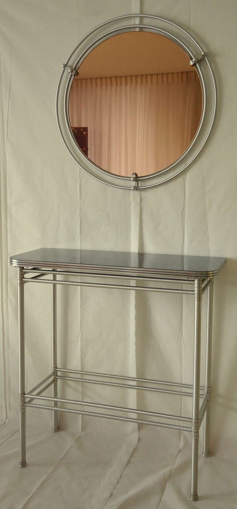A custom ordered Warren McArthur console and mirror c.1938. 

The lightness and vertical height of the console serves as an interesting counterpoint to the weight of the peach mirror. 

 It is highly unusual to have a vintage photograph of the