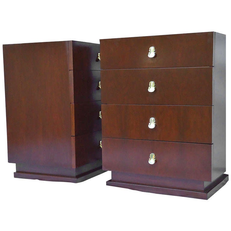 Elegant pair of mid century four drawer dark walnut veneered end tables or nightstands on recessed plinths designed by Merton Gershun for American of Martinsville. 

The drawer faces are book matched veneer  with brass plated cello shaped  finger
