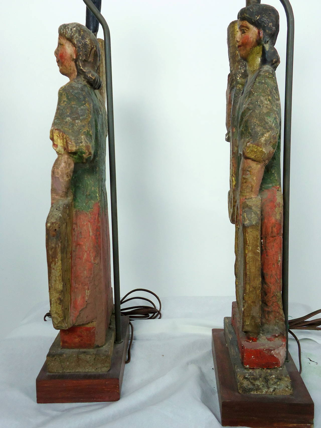 Unusual poly-chromed wooden figurative candleholders carved in Mexico in the late 18th to mid-19th century converted into table lamps, circa 1940.
The figures have had minor restoration over the last century and a half but retain much of their