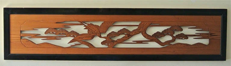 Japanese ramna crafted of carved sugi wood surrounded by a black lacquered frame. The ranma depicts a crane soaring above stylized pines and clouds. 

The ramna would have originally been installed over interior partition doors in a traditional